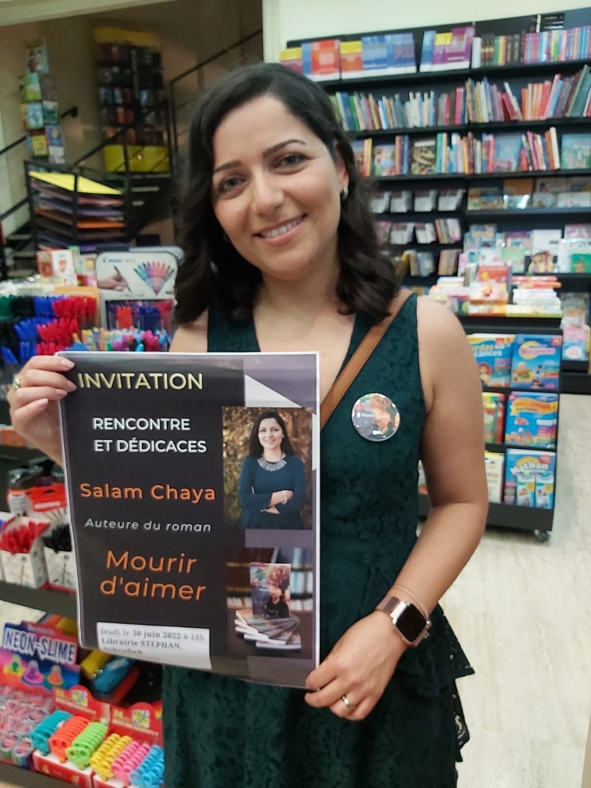 Salam Chaya tenant l'affiche d'invitation « Rencontre et dédicaces — Mourir d'aimer » à la Librairie Stephan