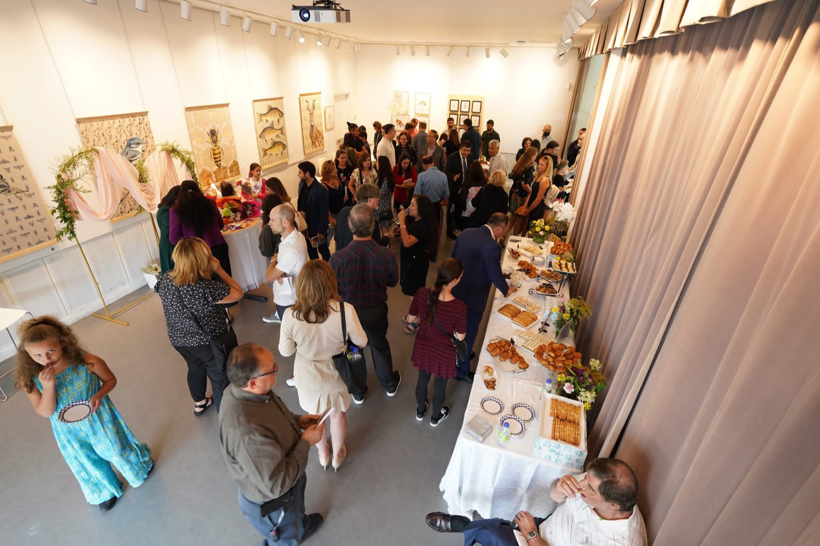 Vue plongeante du buffet et des invités déambulant devant l'exposition d'œuvres animalières