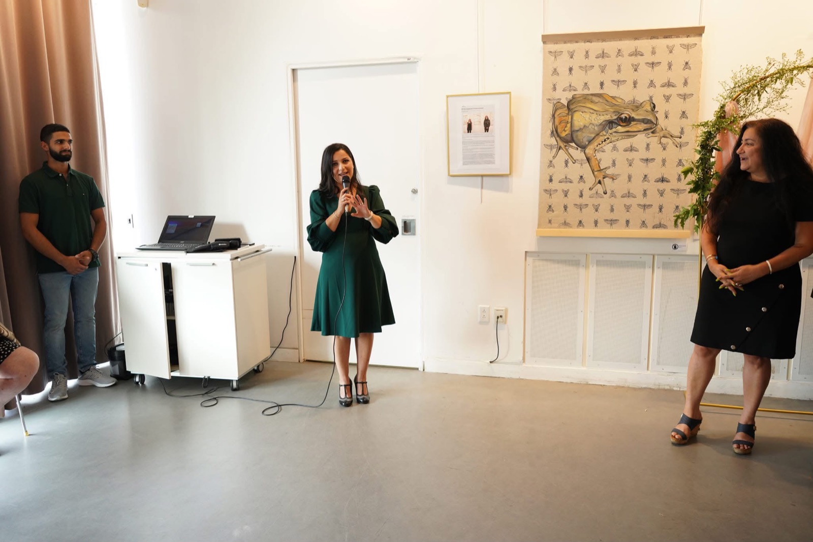 Salam Chaya en robe verte prononçant un mot au micro à la Bibliothèque Raymond-Lévesque