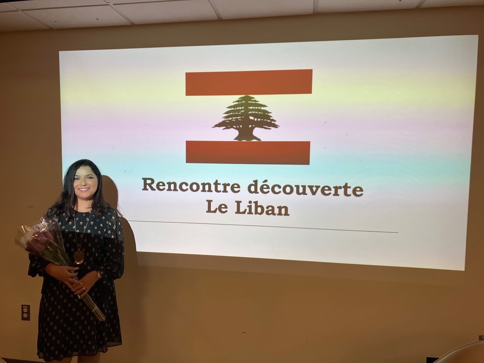 Salam Chaya souriante, bouquet à la main, devant la projection « Rencontre découverte — Le Liban »